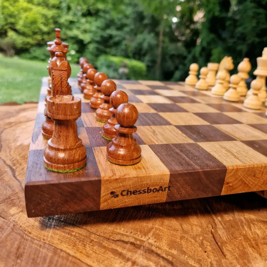 Hölzernes Schachbrett mit aufgestellten Figuren im Garten